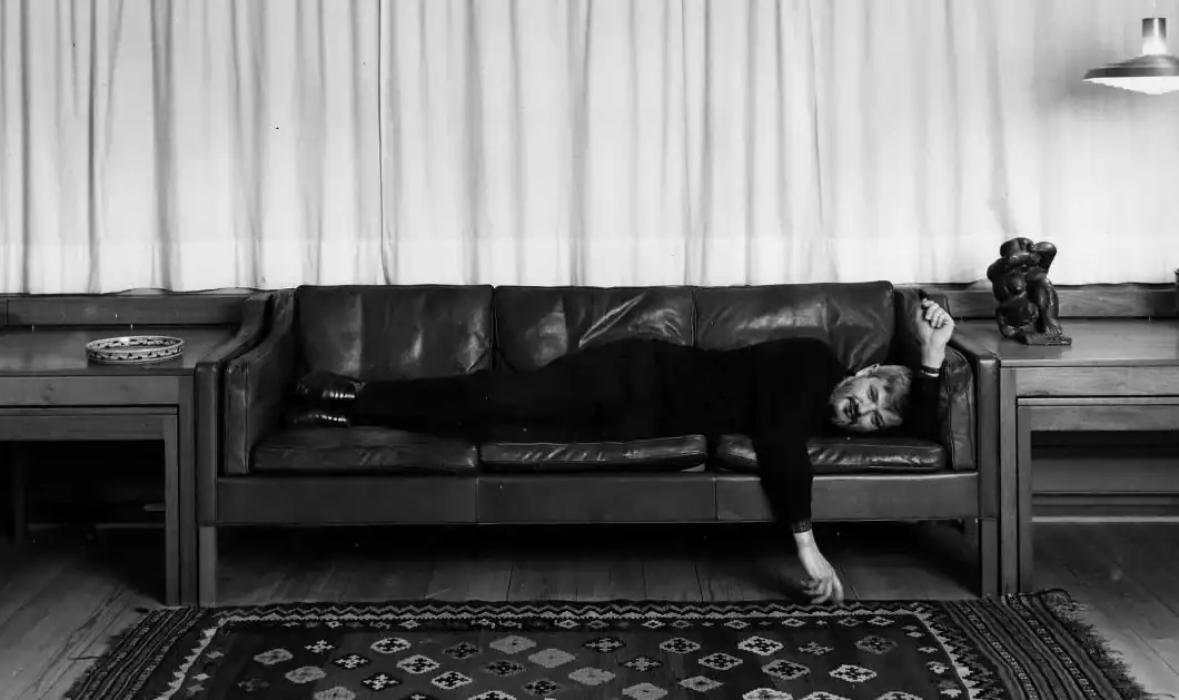 Le designer danois Borge Mogensen, allongé sur son canapé Sofa Embassy
